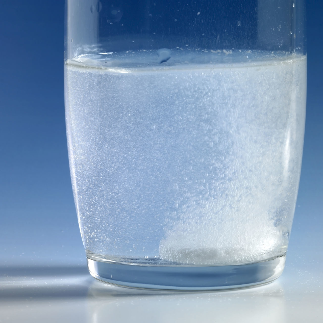 CLOSE-UP OF DRINK IN GLASS AGAINST WATER AGAINST BLUE BACKGROUND