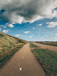 Road amidst field against sky