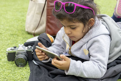 Cute girl using phone on grassy field 