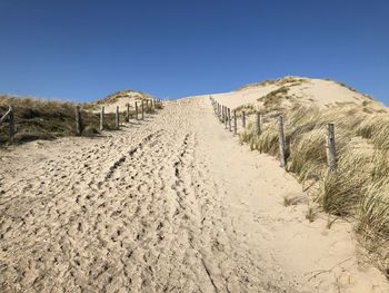 Panoramic view of desert land against clear blue sky