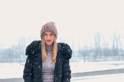 Portrait of smiling young woman standing during winter