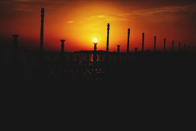 Silhouette factory against sky during sunset