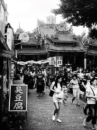 People walking on street in city against sky