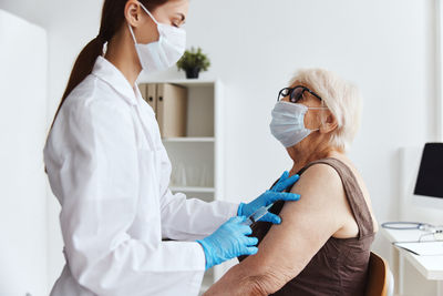 Doctor vaccinating senior woman at hospital