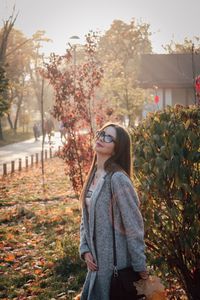 Portrait of young woman standing against autumn plants