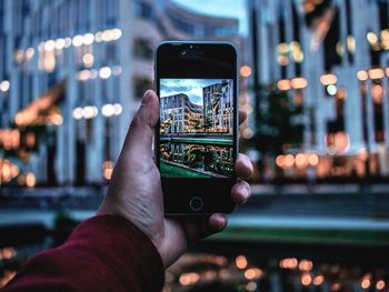 Close-up of hand holding mobile phone in city