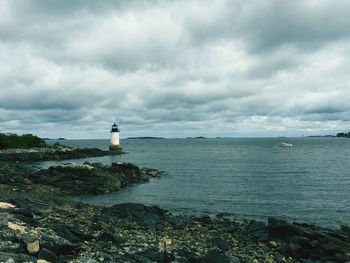 Lighthouse by sea against sky