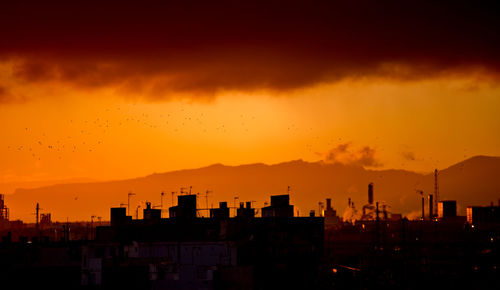 Silhouette buildings against sky during sunset