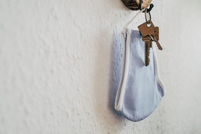 Close-up of keychain hanging in front of everyday mask on wall