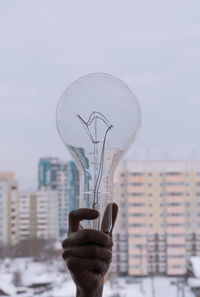 Close-up of hand holding glass against sky