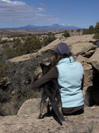 Rear view of woman with dog against sky