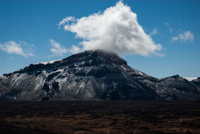 Scenic view of volcanic mountain against blue sky