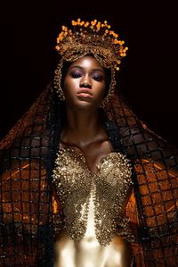 Portrait of woman in costume standing against black background