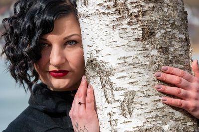 Close-up portrait of young woman with tree trunk