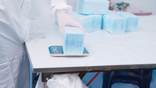 Midsection of person measuring masks on weight scale