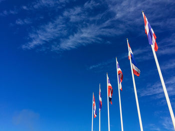Low angle view of thai flags in row against blue sky