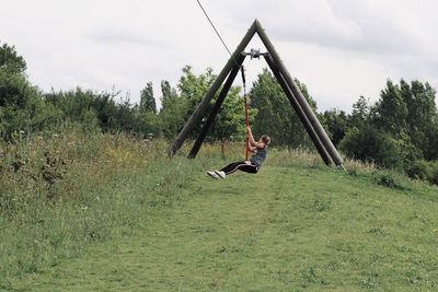 Girl sitting on field against sky