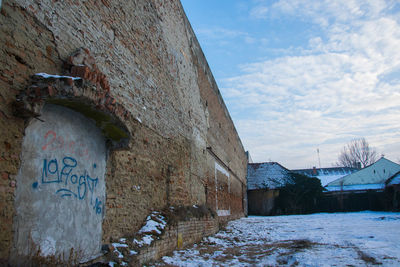 Graffiti on wall against sky during winter