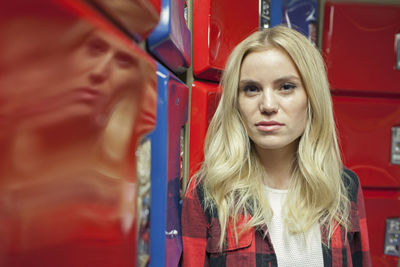 A young owmn in front of some red and blue lockers.