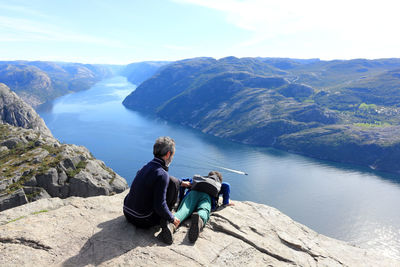 Father holding son lying on cliff by river