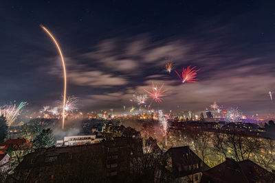 Firework display in city against sky at night