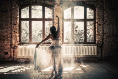 Rear view of bride with arms raised standing on floor