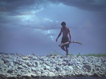 Full length of shirtless man in sea against sky