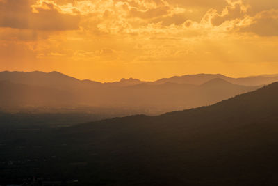 Scenic view of silhouette mountains against orange sky