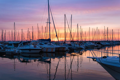 Sailboats moored at harbor during sunset