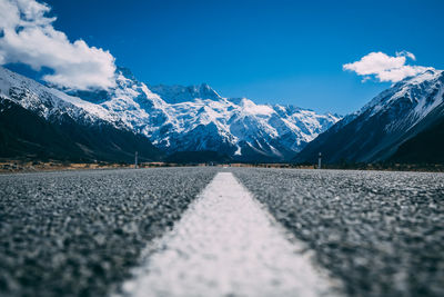 Road leading towards snowcapped mountains against sky