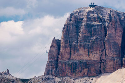 Low angle view of rock formation against clouds