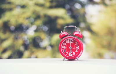 Close-up of red alarm clock on table at yard