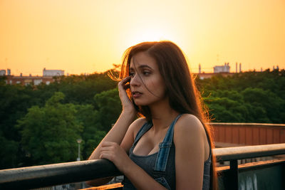 Close-up of woman against railing at sunset