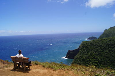 Rear view of man sitting on bench looking at horizon