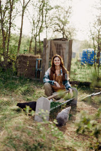 Young woman using mobile phone while sitting on field