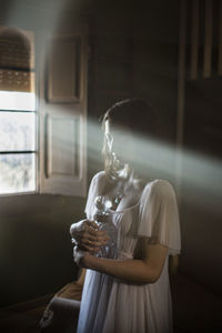 Young woman holding glass jar standing at home