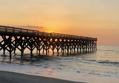 Pier over sea against sky during sunset