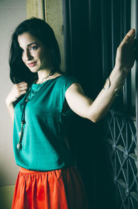 Beautiful woman looking away while standing by metal gate