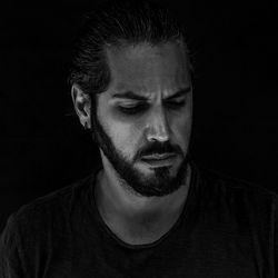 Close-up portrait of young man against black background