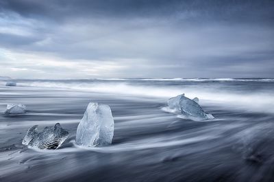 Scenic view of glacier on beach in sea during winter