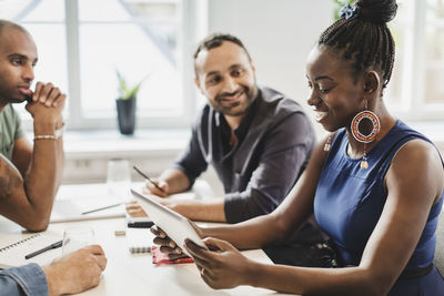 Friends looking at woman using digital tablet in language class