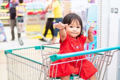 Portrait of cute baby girl sitting in shopping cart