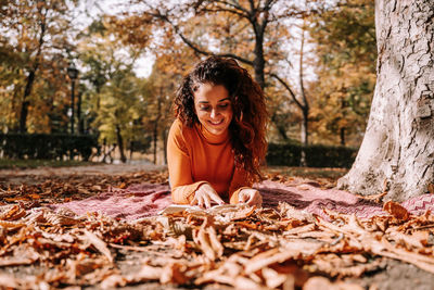Portrait of a smiling young woman with autumn leaves