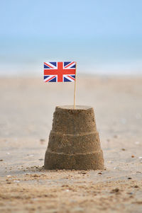 British flag on sandcastle at sandy beach