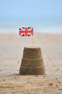 British flag on sandcastle at sandy beach