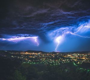 Lightning over illuminated cityscape at night