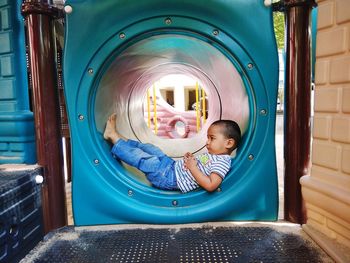 Side view full length of boy lying down in tunnel slide