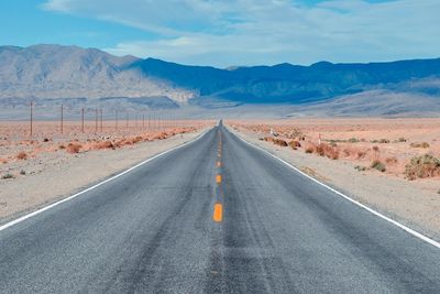 Road leading towards mountains against sky