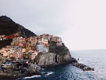 Buildings by sea against sky