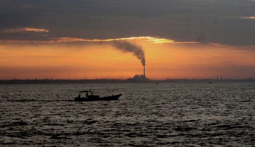 Silhouette ship on sea against sky during sunset